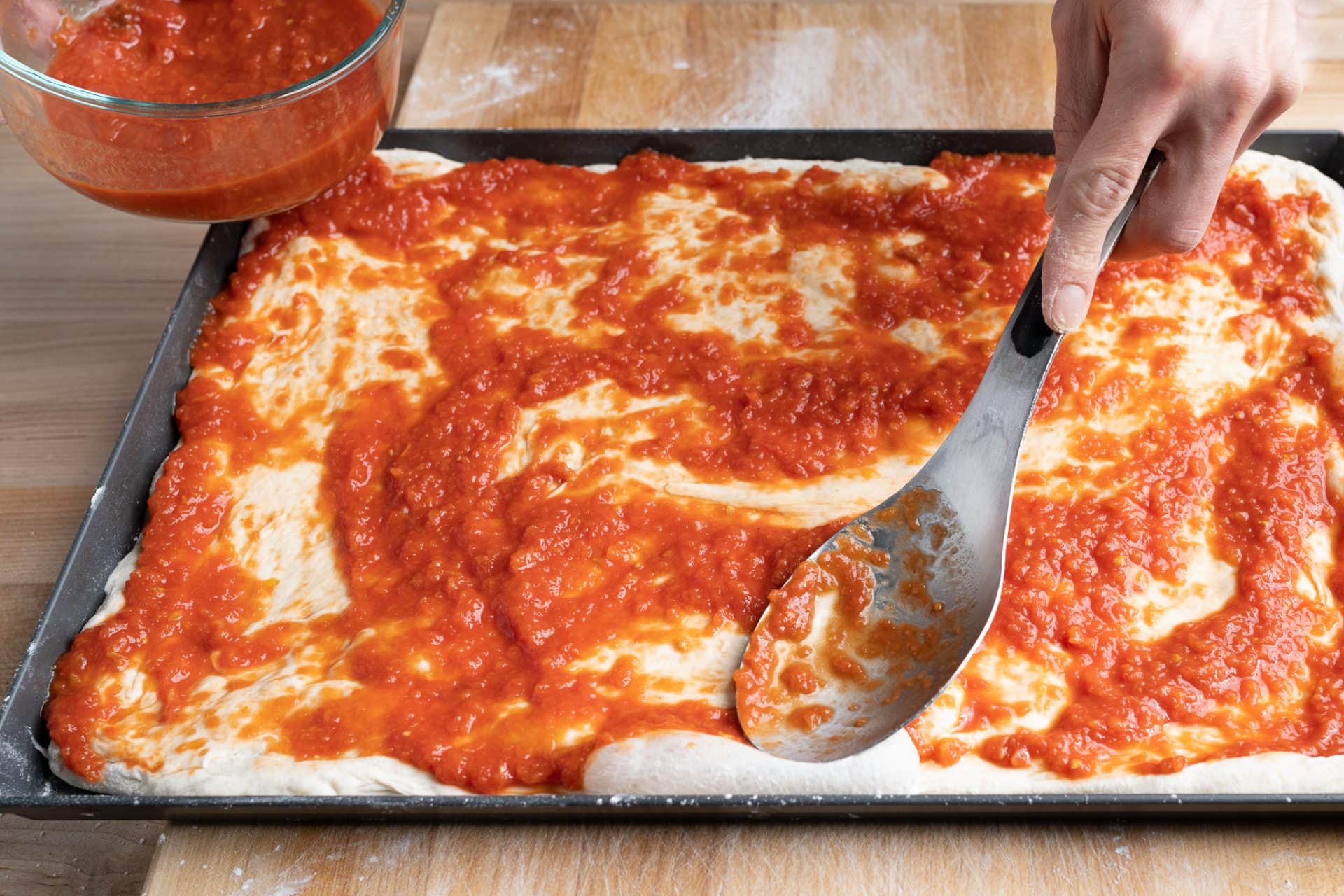 Spreading tomato sauce.