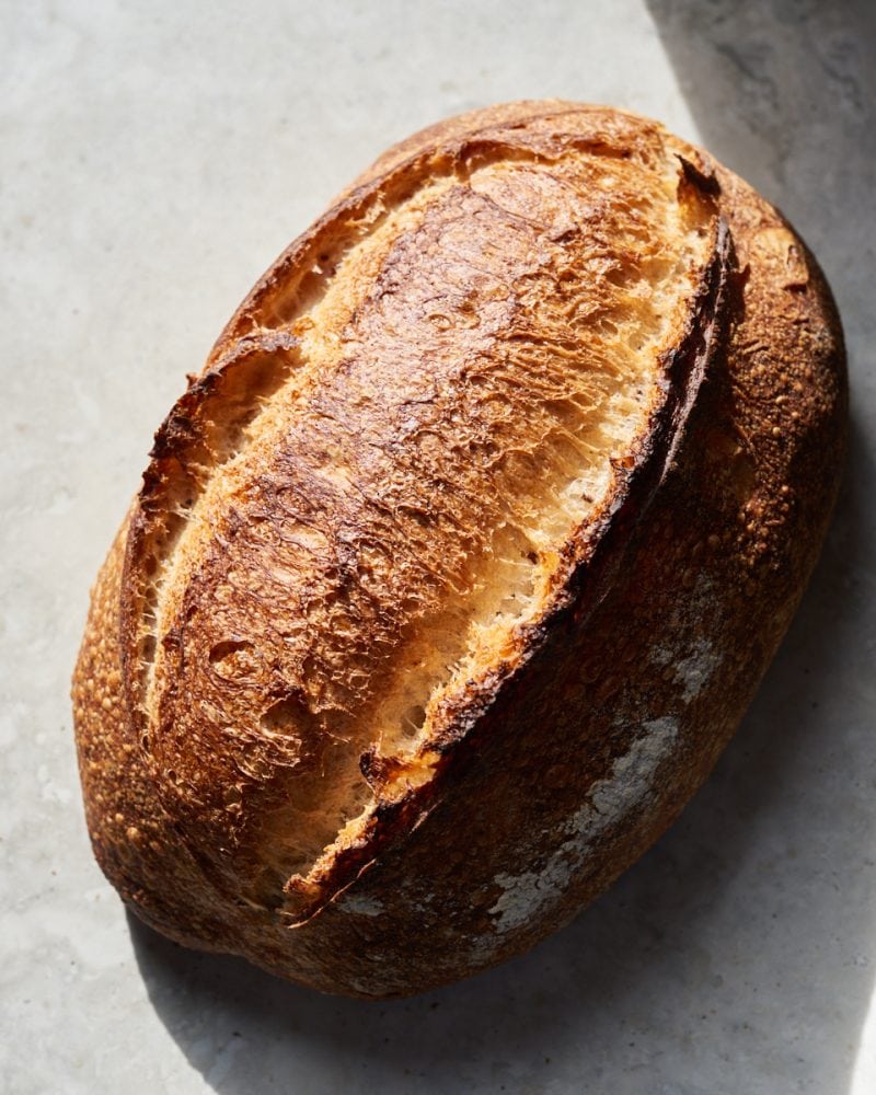 A loaf of sourdough bread baked and sitting on a table.