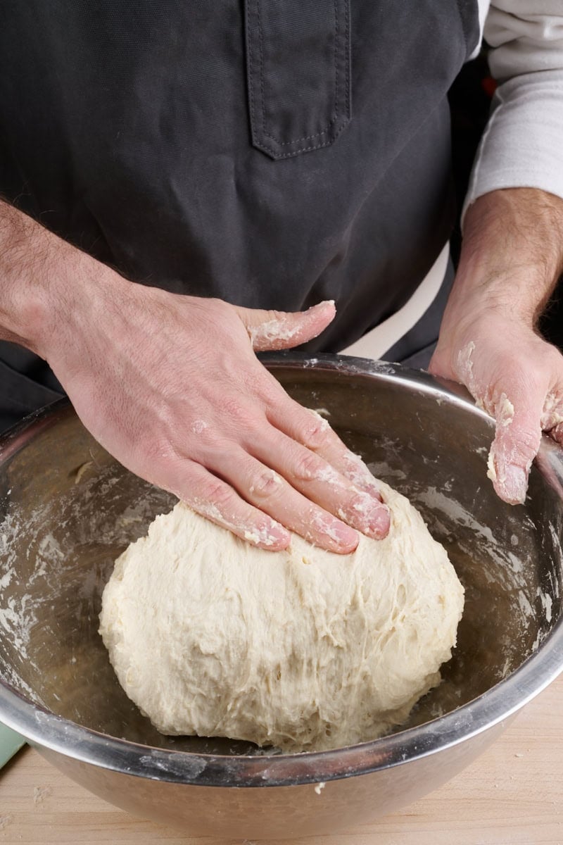 Mixing bread dough by hand with folds in the mixing bowl.