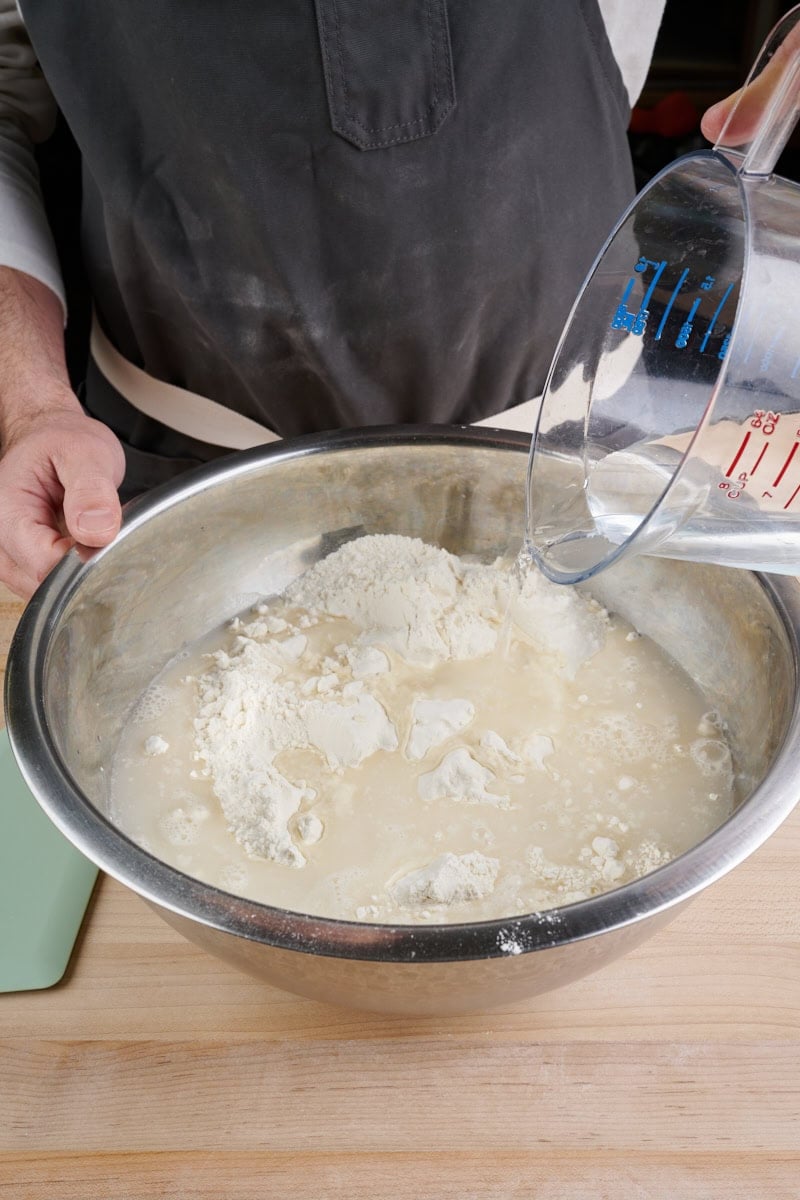 Adding water to flour before mixing bread dough.
