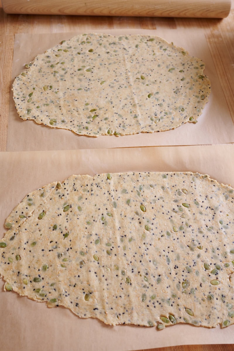 Rolled out seeded cracker dough on parchment paper.